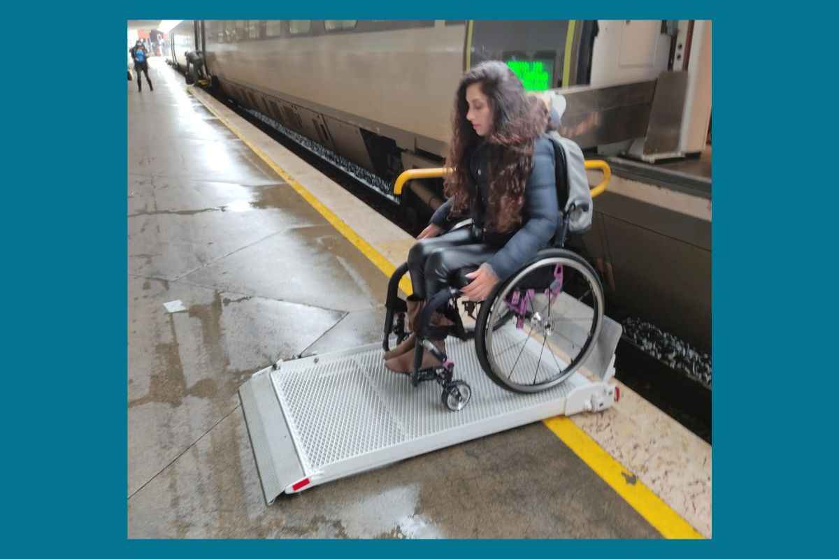 Pessoa que utiliza cadeira de rodas a descer de um comboio em plataforma elevatória