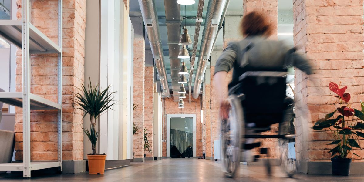 Mulher a andar de cadeira de rodas num corredor interior
