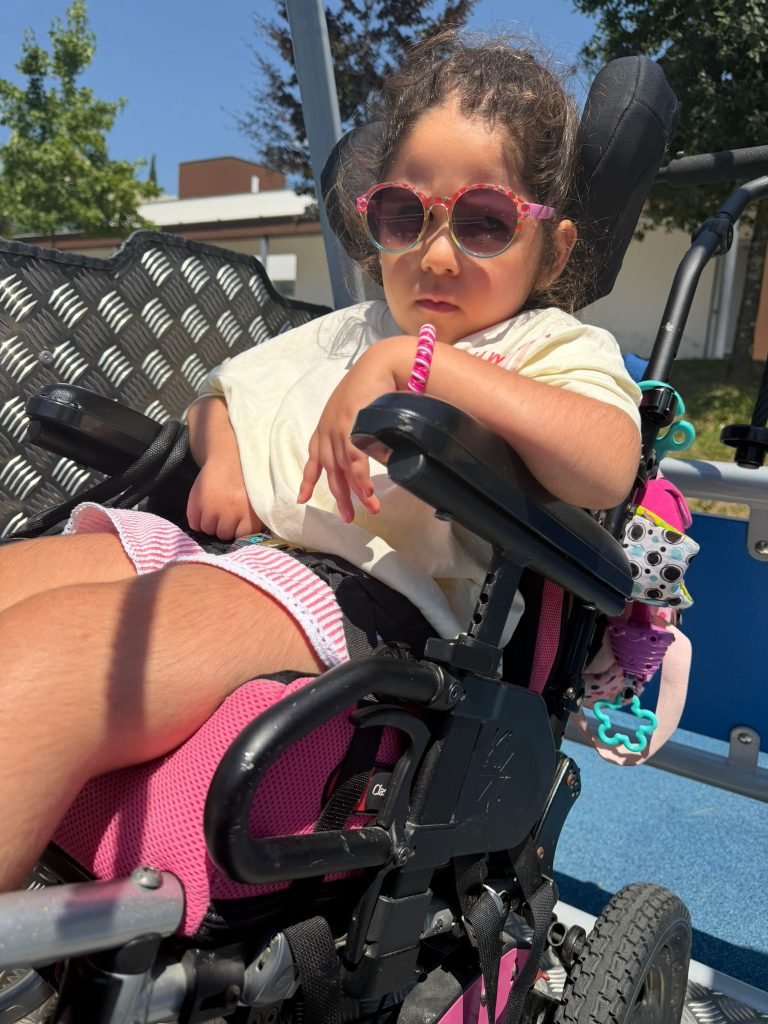 Criança sentada numa cadeira de rodas